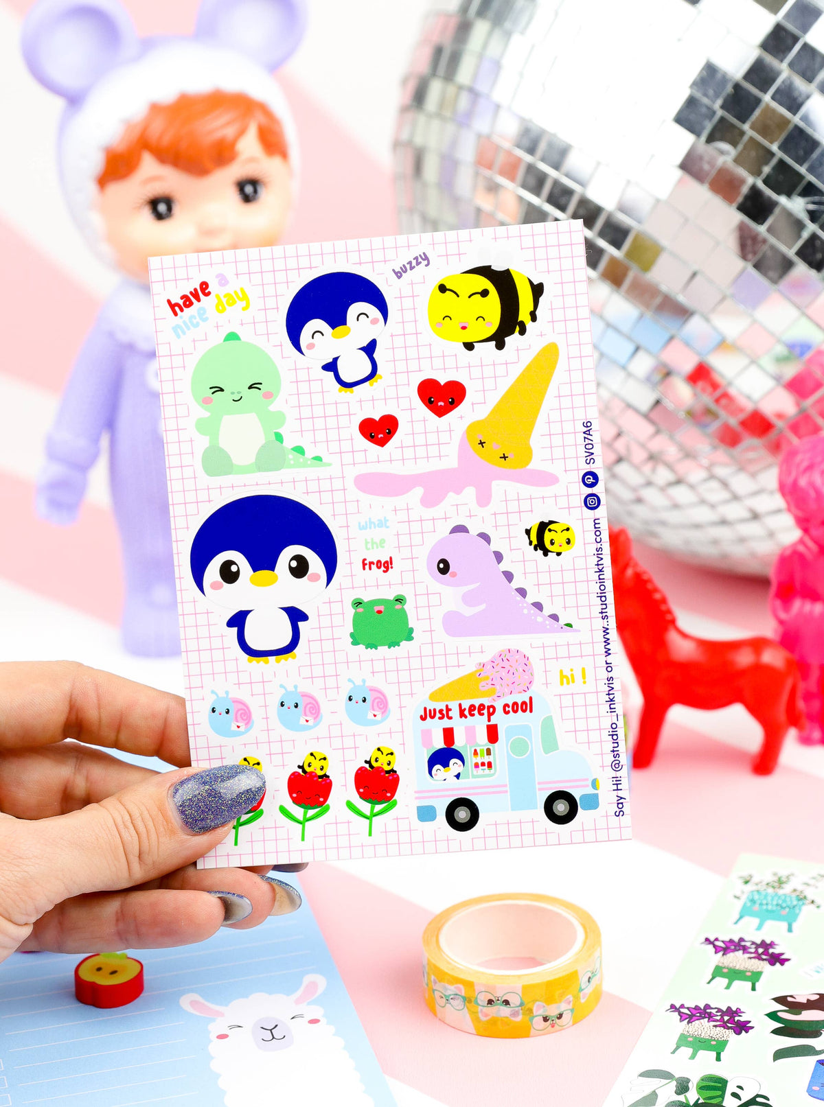 Sticker sheet held in hand with penguins, frog, bees, and ice cream truck stickers