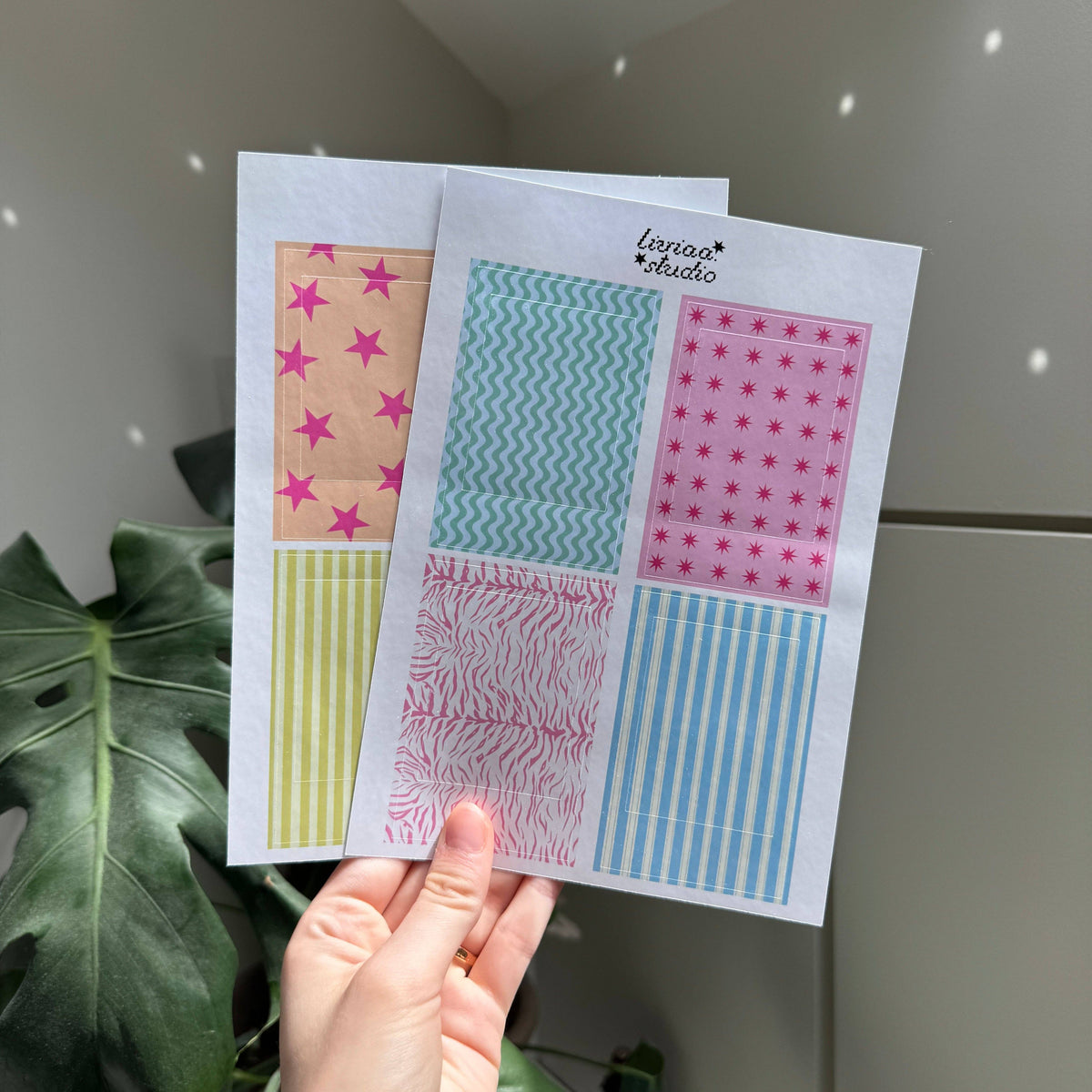 Polaroid frame sheets held in hand, showing teal wavy, pink star, zebra, and striped borders