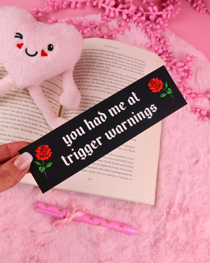 Black bookmark with red rose and green text on open book