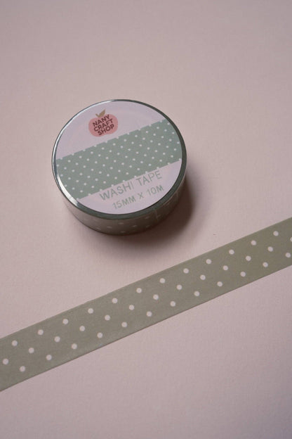 Green polka-dot washi tape roll with white dots and patterned strip on tabletop