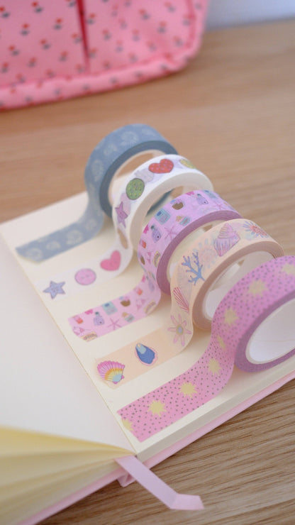 Pastel washi tape rolls with seashells, corals, and stars; tape ends fanned out
