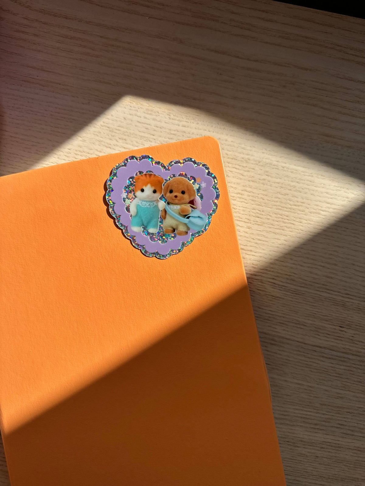 Glitter vinyl heart sticker with two teddy bear friends on orange backing