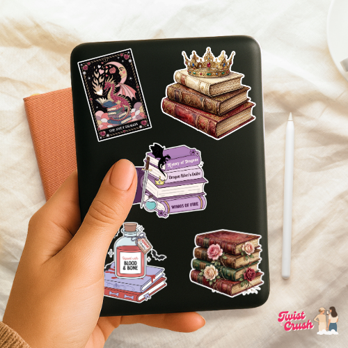 Sticker sheet held in hand with dark backing and book-themed dragon, crown, and books