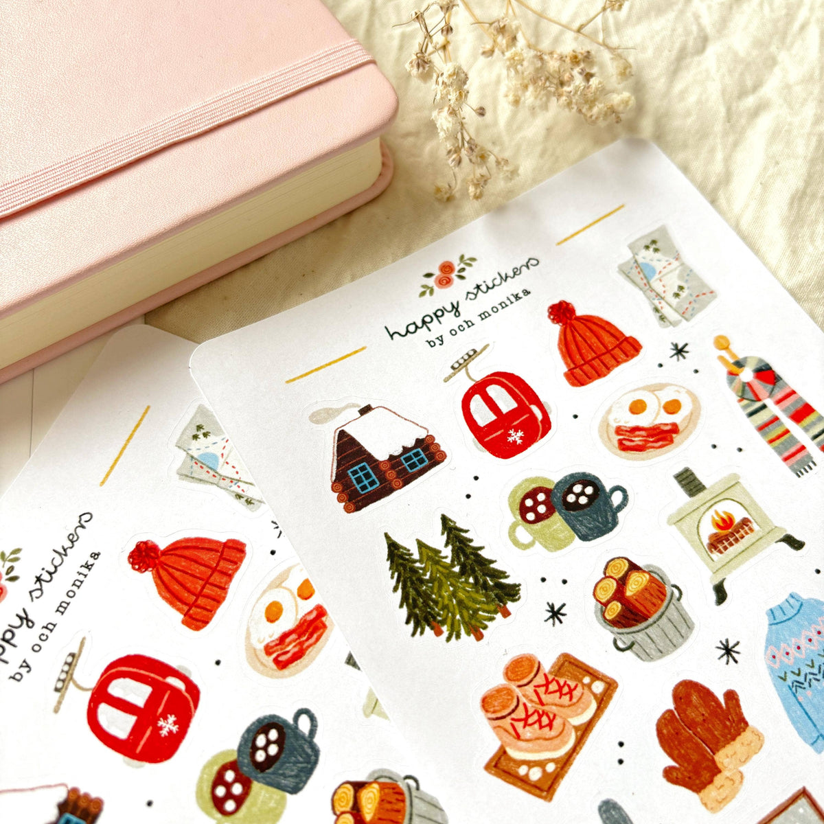 Angle view of winter sticker sheet with hat, lantern, scarf, food, and pine branch icons