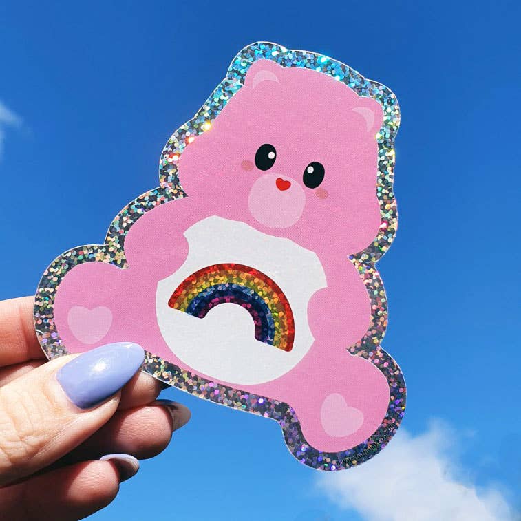 Glitter care bear rainbow sticker held in hand, pink bear with blue glitter outline