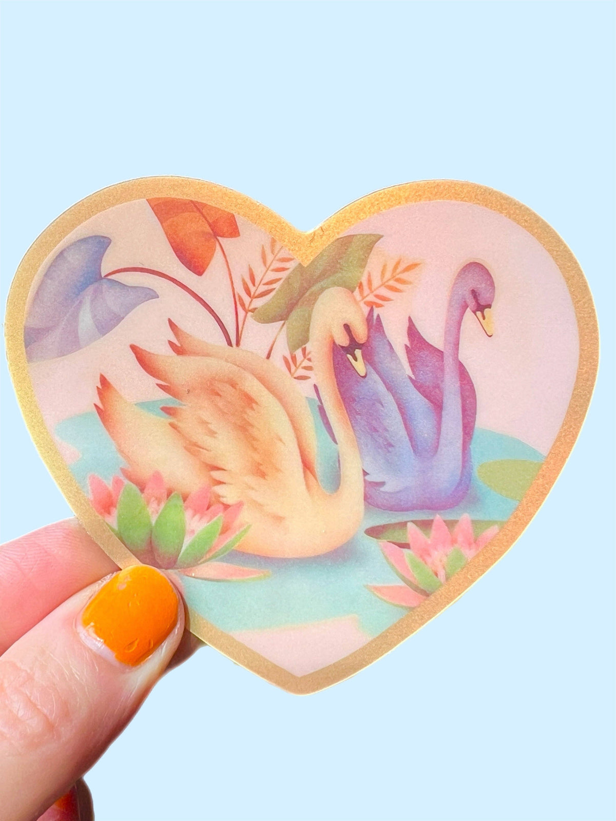 Heart-shaped Swan Friends sticker, 3 inch, with swans and floral leaves, held in hand