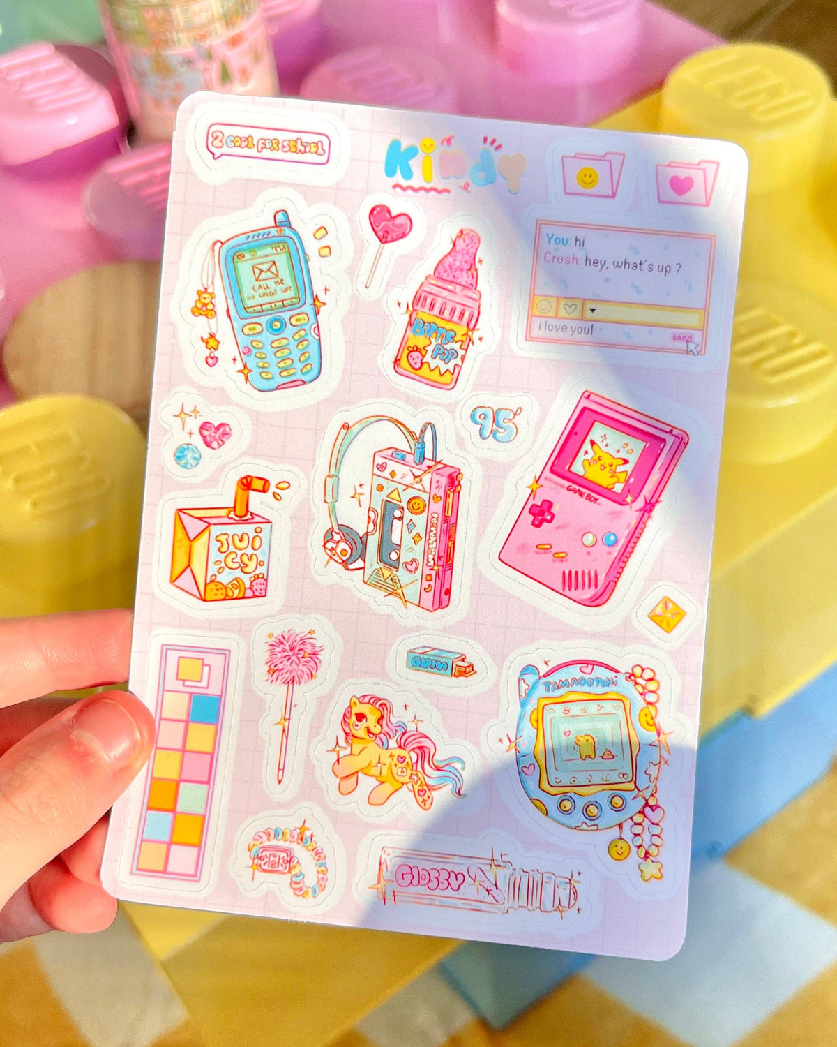 90s Kid sticker sheet in hand with retro consoles, cake, hearts, and notes