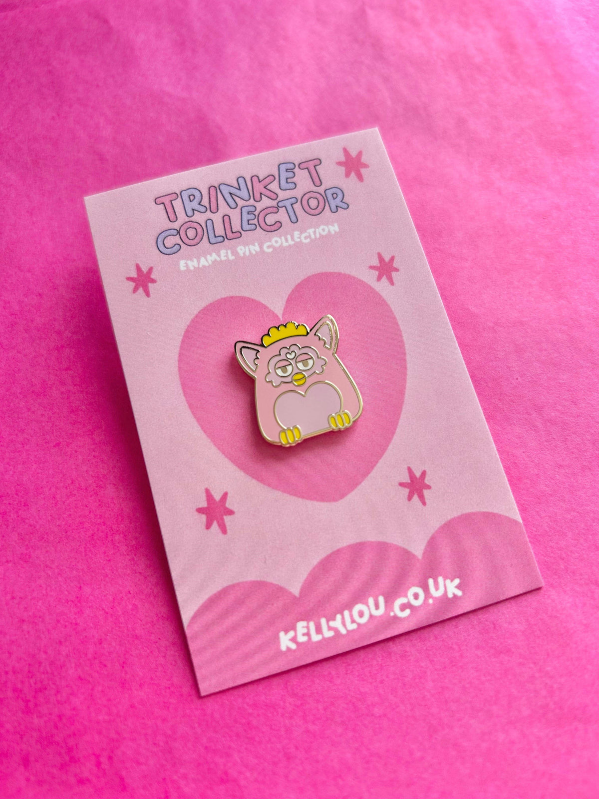 Grey cartoon cat enamel pin with yellow crown on pale pink collector card