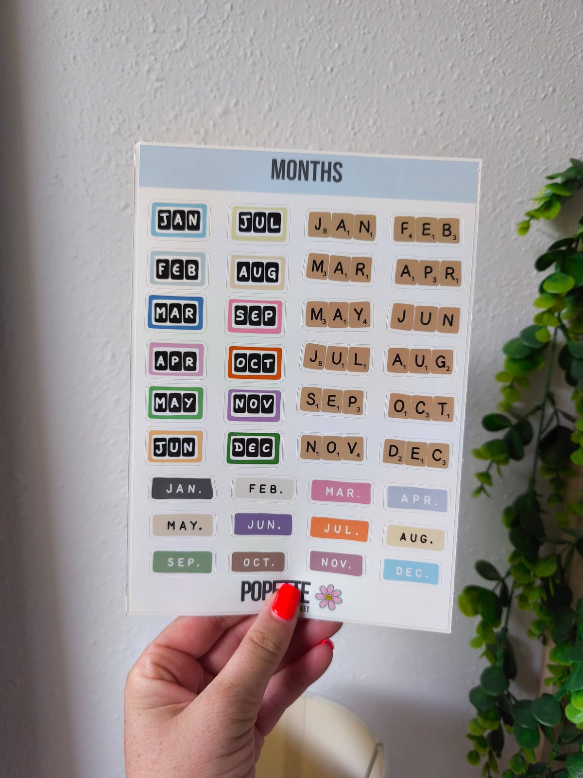 Months sticker sheet held in hand, with colorful month abbreviations and POPETTE logo