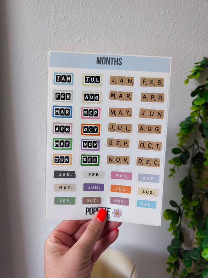 Months sticker sheet held in hand, with colorful month abbreviations and POPETTE logo