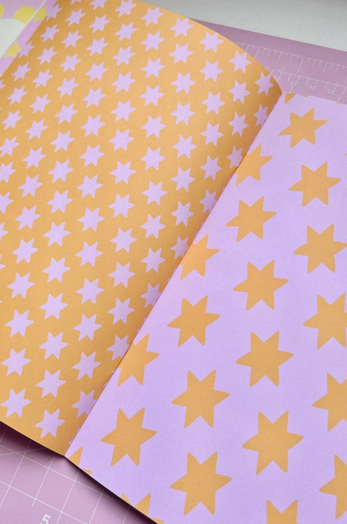 A5 deco papers book, overlapping star-pattern sheets in peach, lavender, and yellow with pale stars