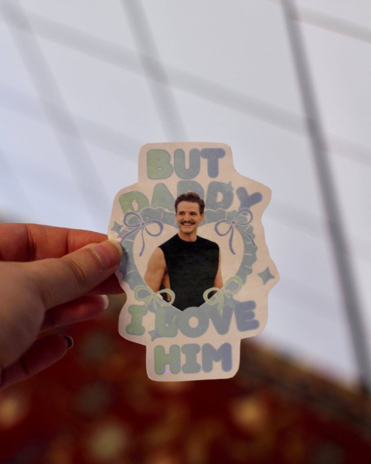 Hand holding clear blue sticker with man portrait and “DADDY I LOVE HIM” wording