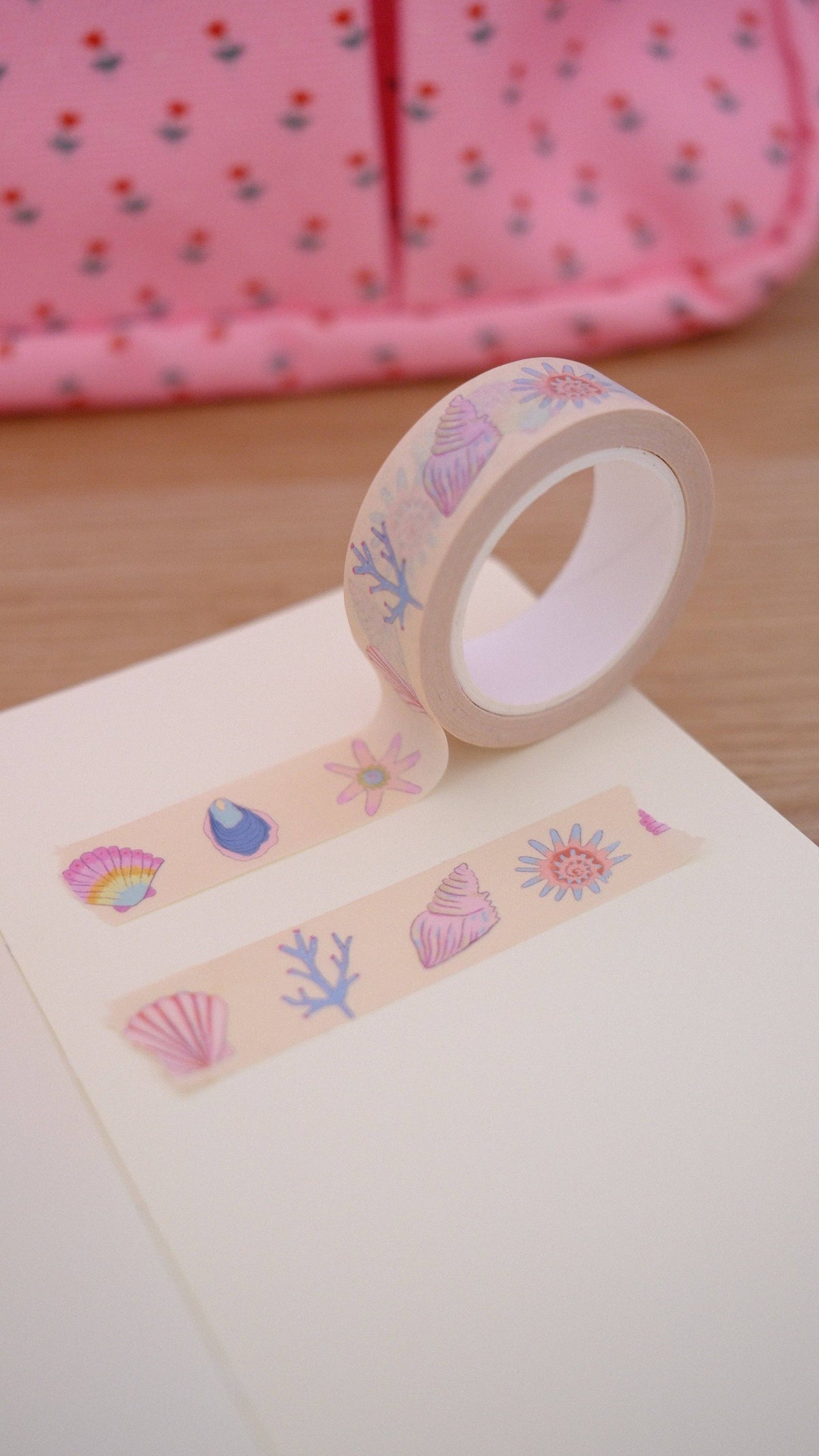 Beige washi tape roll with pastel seashell and coral motifs, tape strip shown