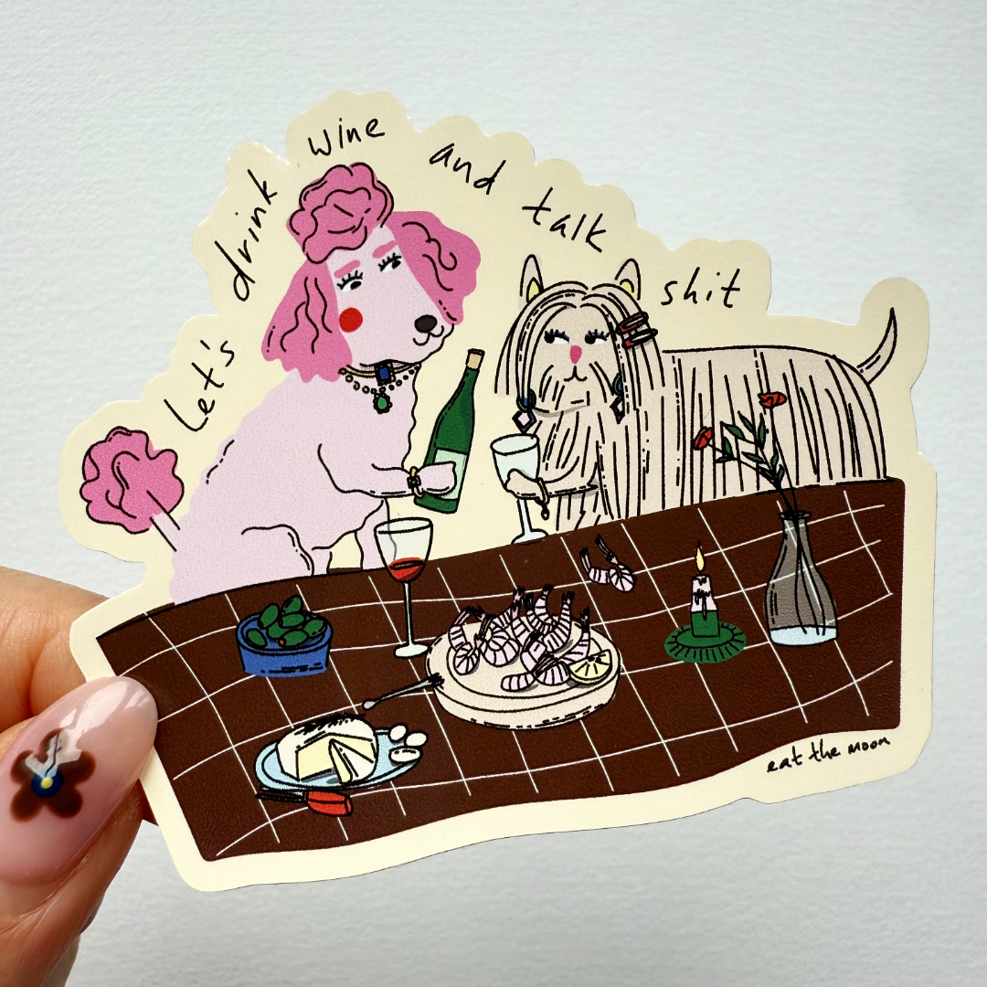 Handheld wine-themed die-cut vinyl sticker showing pink dog with drink and cat at a table