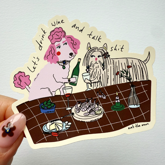 Handheld wine-themed die-cut vinyl sticker showing pink dog with drink and cat at a table
