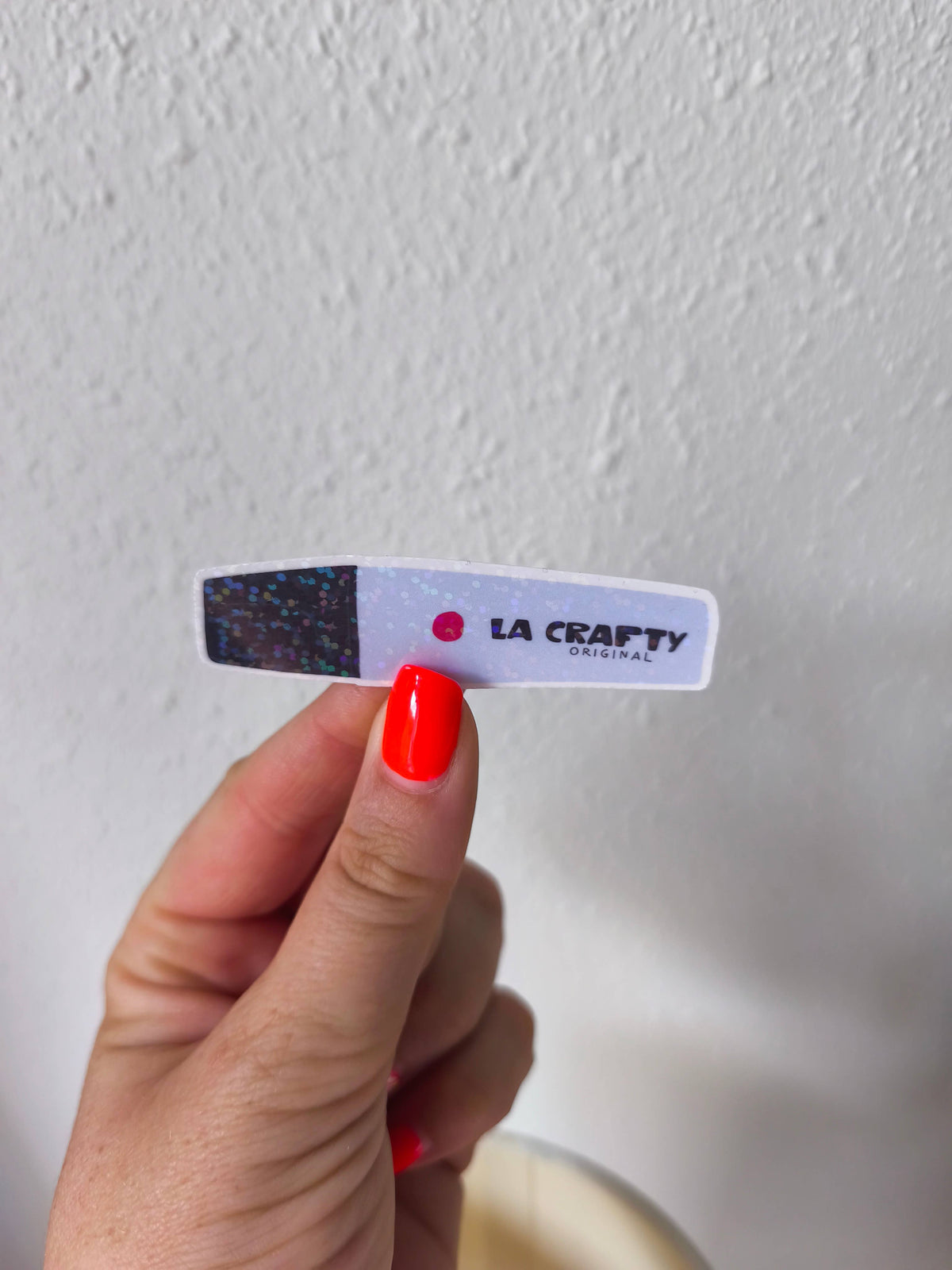 La crafty sticker on wall, white rounded label with black speckle end and red dot logo
