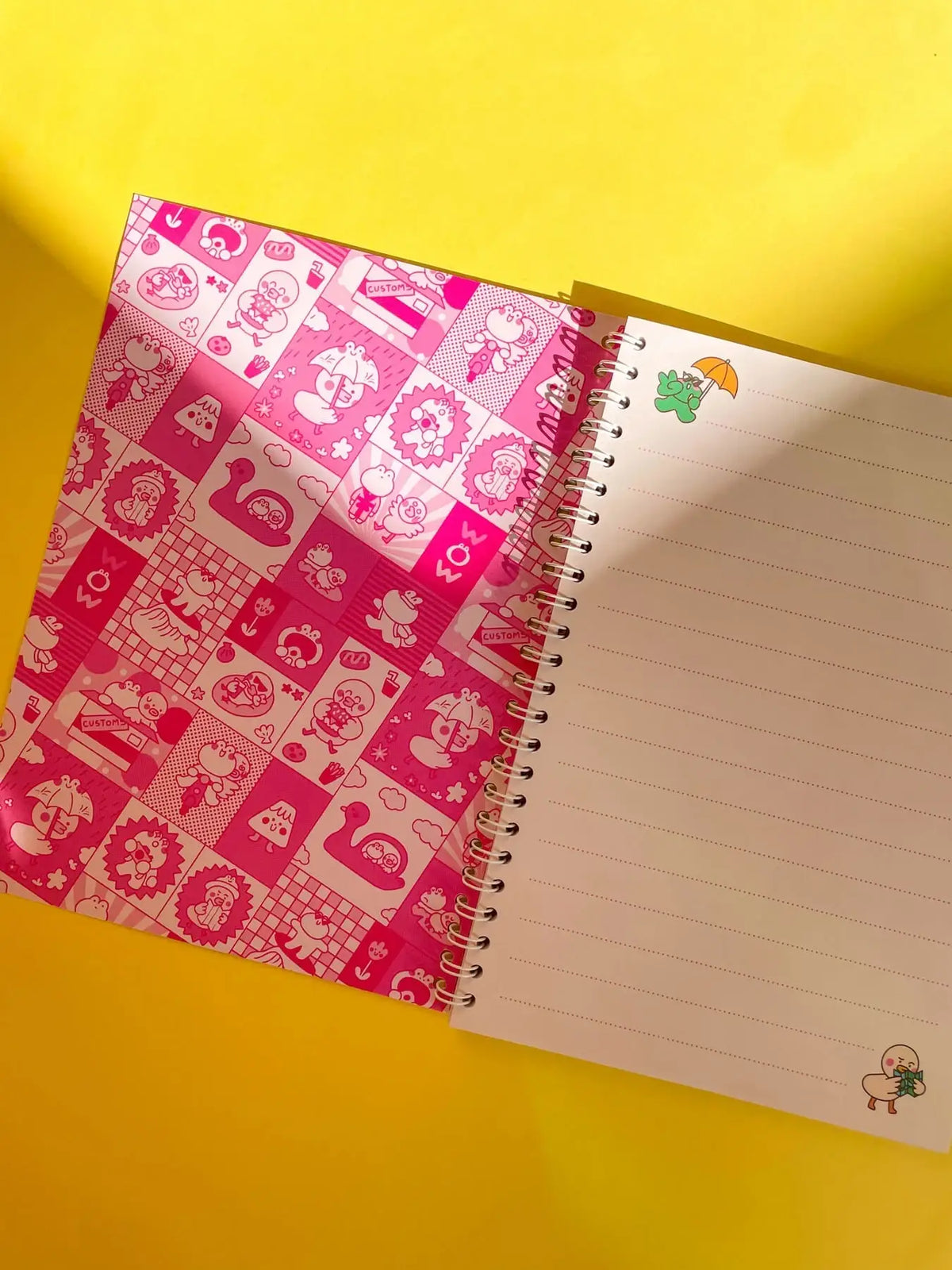 Open spiral notebook with pink patterned left page and lined right page