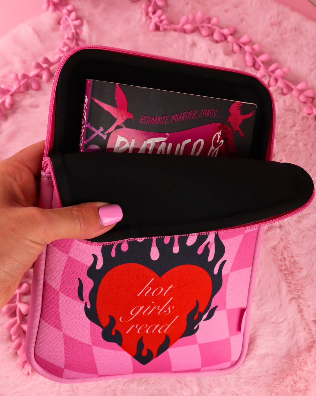 Pink checkered e-reader sleeve with zip, hand holding front pouch with tablet inside