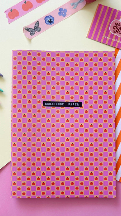 A5 scrapbook paper sheet with pink background and small purple square icons, centered