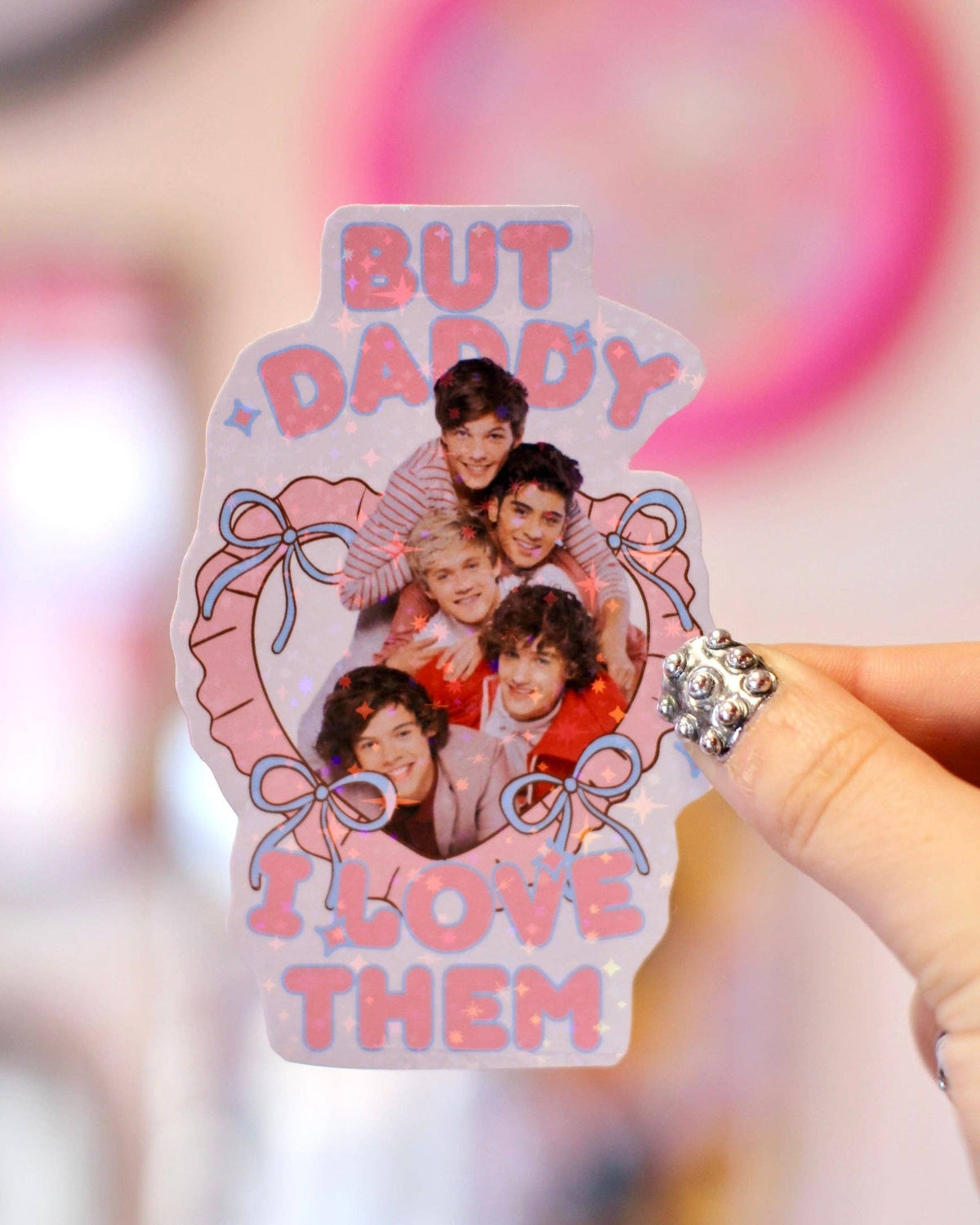 Hand holding One Direction But Daddy I Love Them sticker, iridescent pink-purple photo design
