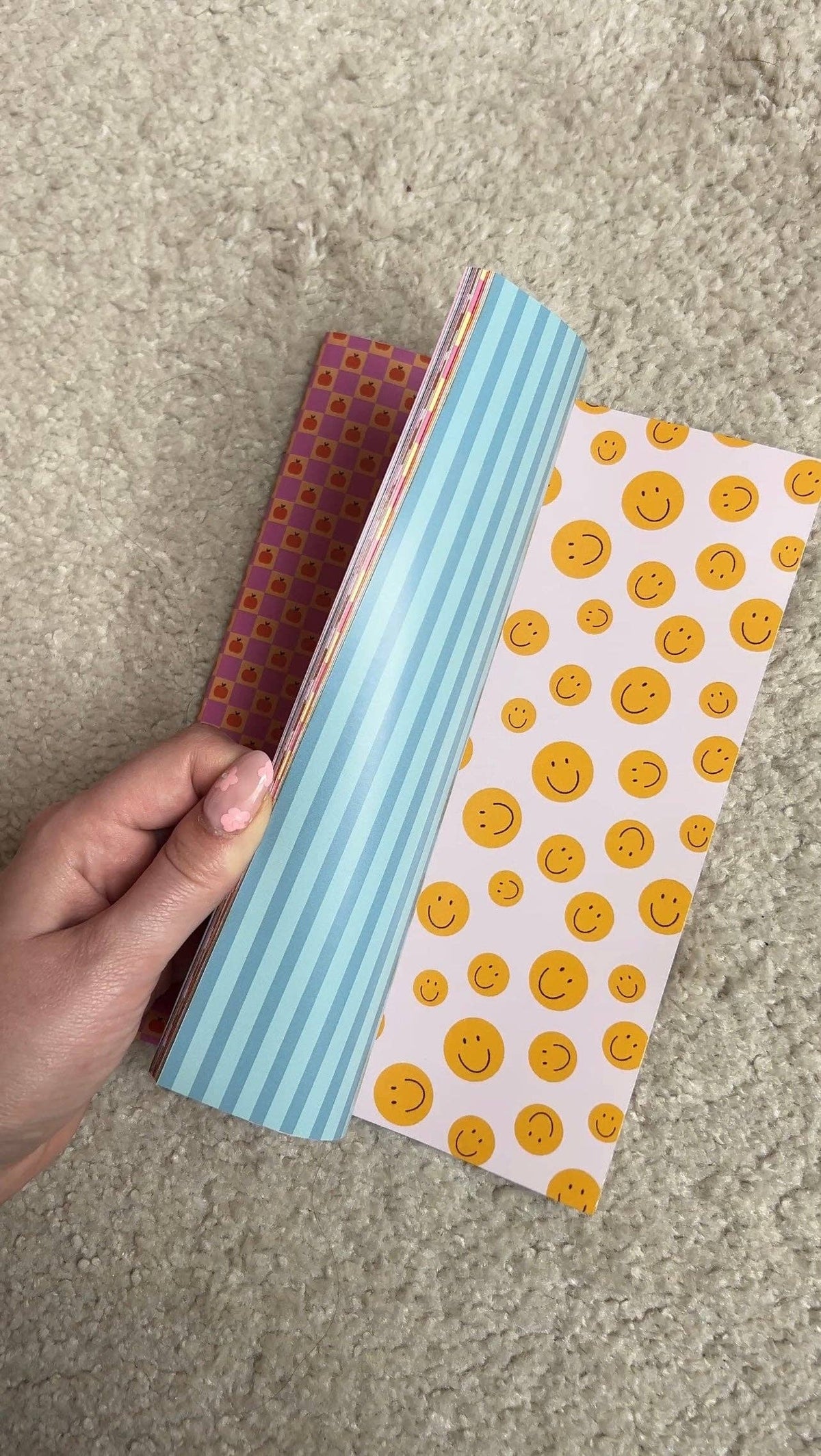 Stack of scrapbook paper sheets, blue stripes and yellow smiley pattern on top