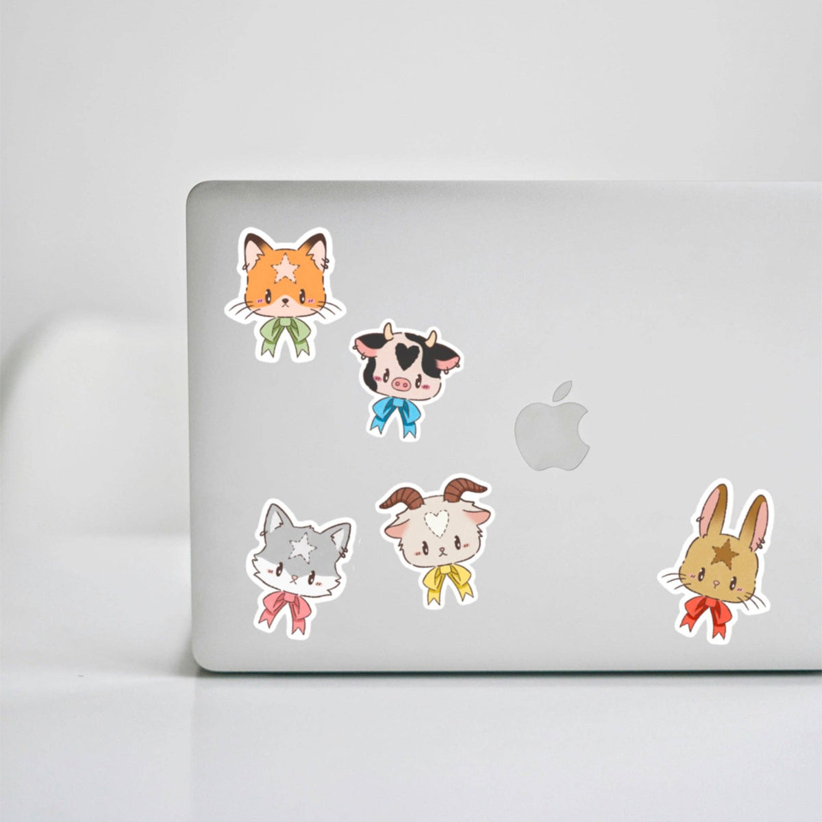 Mystery animal stickers on laptop: orange cat, cow, gray cat, and rabbit