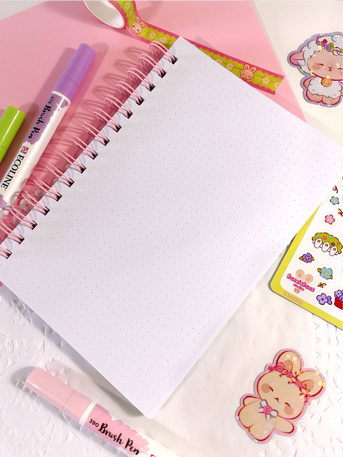 Open spiral notebook with white dotted pages and cute character stickers on the side