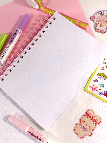 Open spiral notebook with white dotted pages and cute character stickers on the side