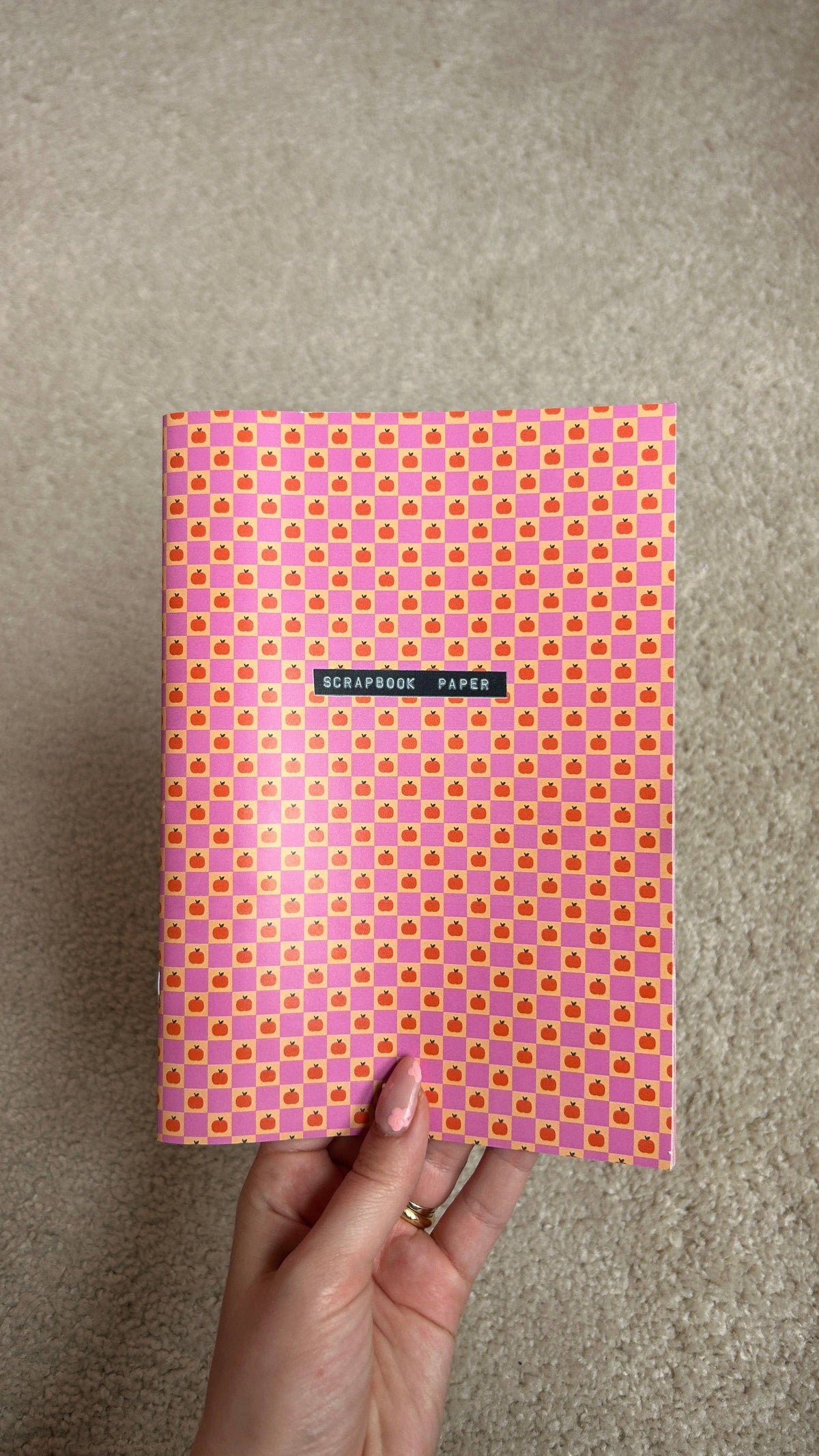 A5 scrapbook paper sheet with pink-and-purple small square pattern, held in hand