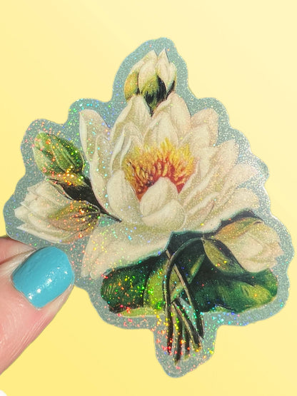 White lotus flower sticker with sparkly white blooms, dark green base, held by fingers
