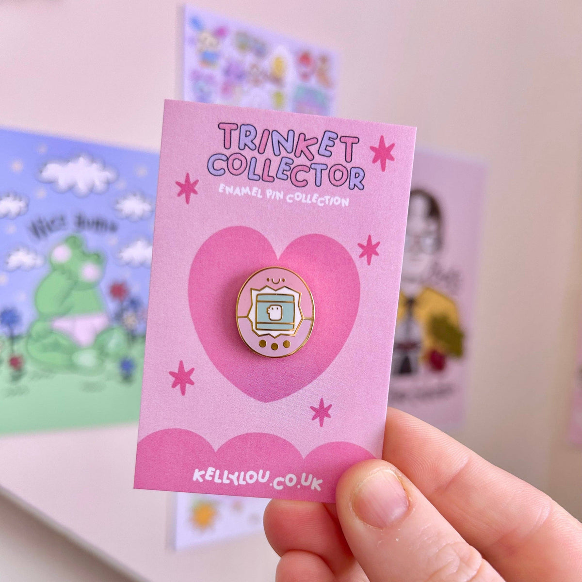Round mini enamel pin featuring a cartoon virtual pet with a screen and face.