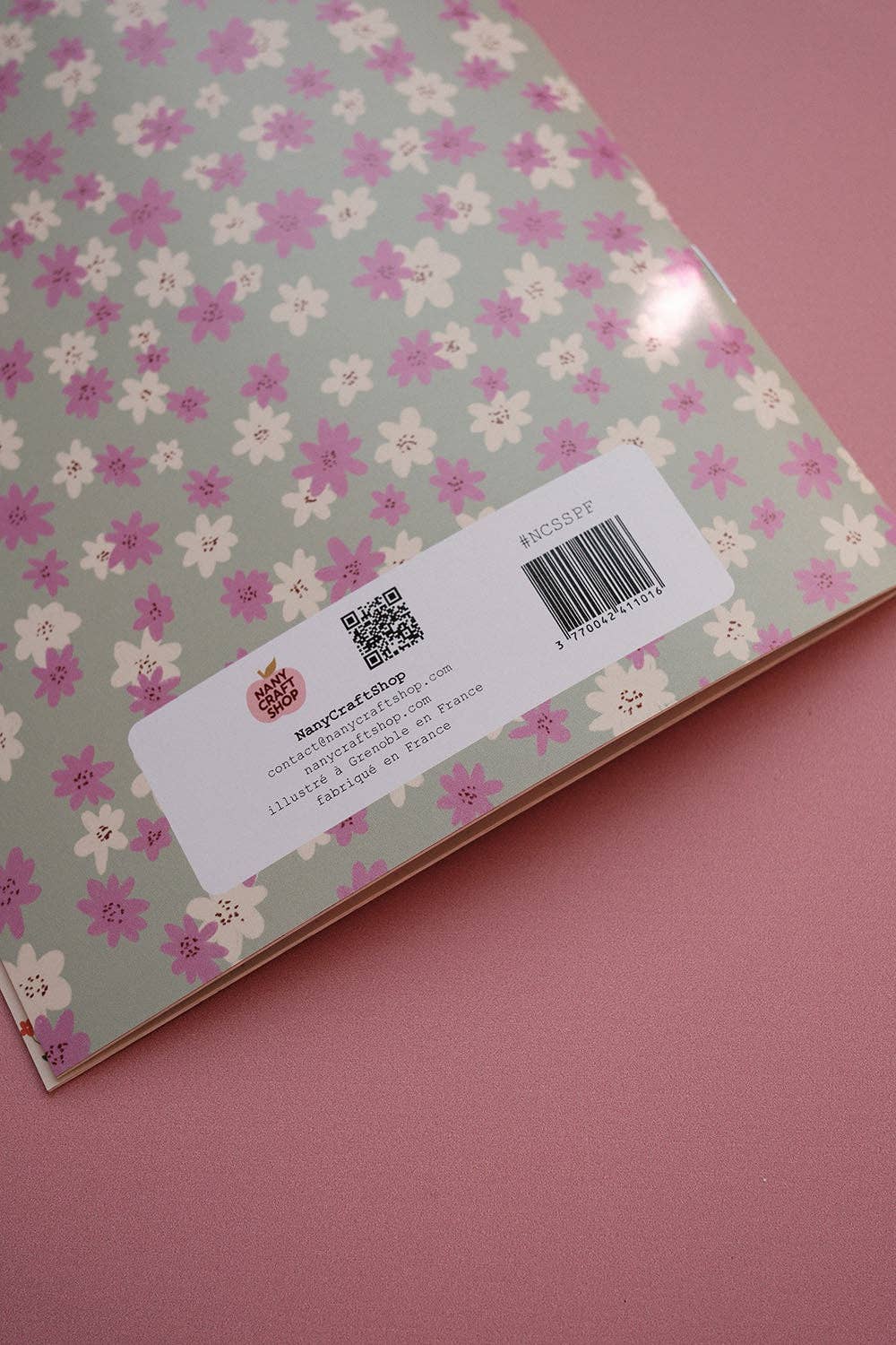 Scrapbook paper sheet with small floral pattern on back and barcode label near bottom