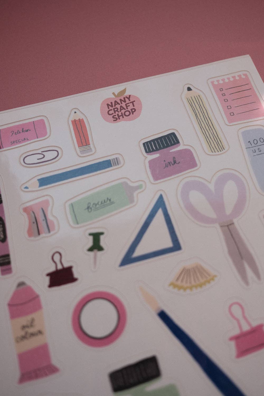 Closeup of stationery-themed sticker sheet with pens, pencils, scissors, and heart shapes