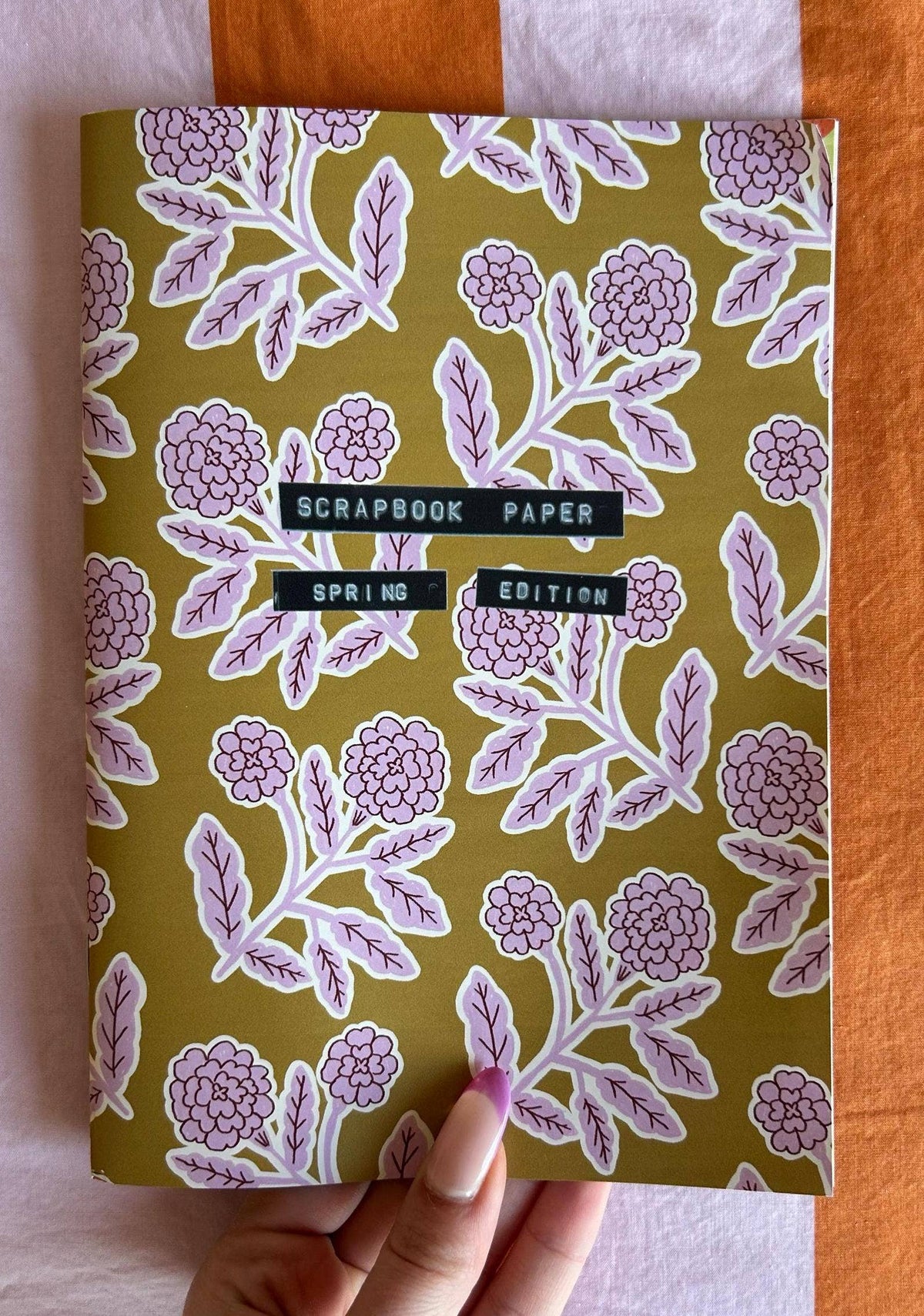 A5 scrapbook paper sheet with lilac floral vines and flowers, held by hand