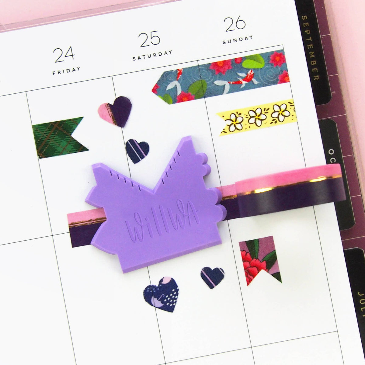 Purple house-shaped washi cutter placed on a planner page next to decorative tape strips