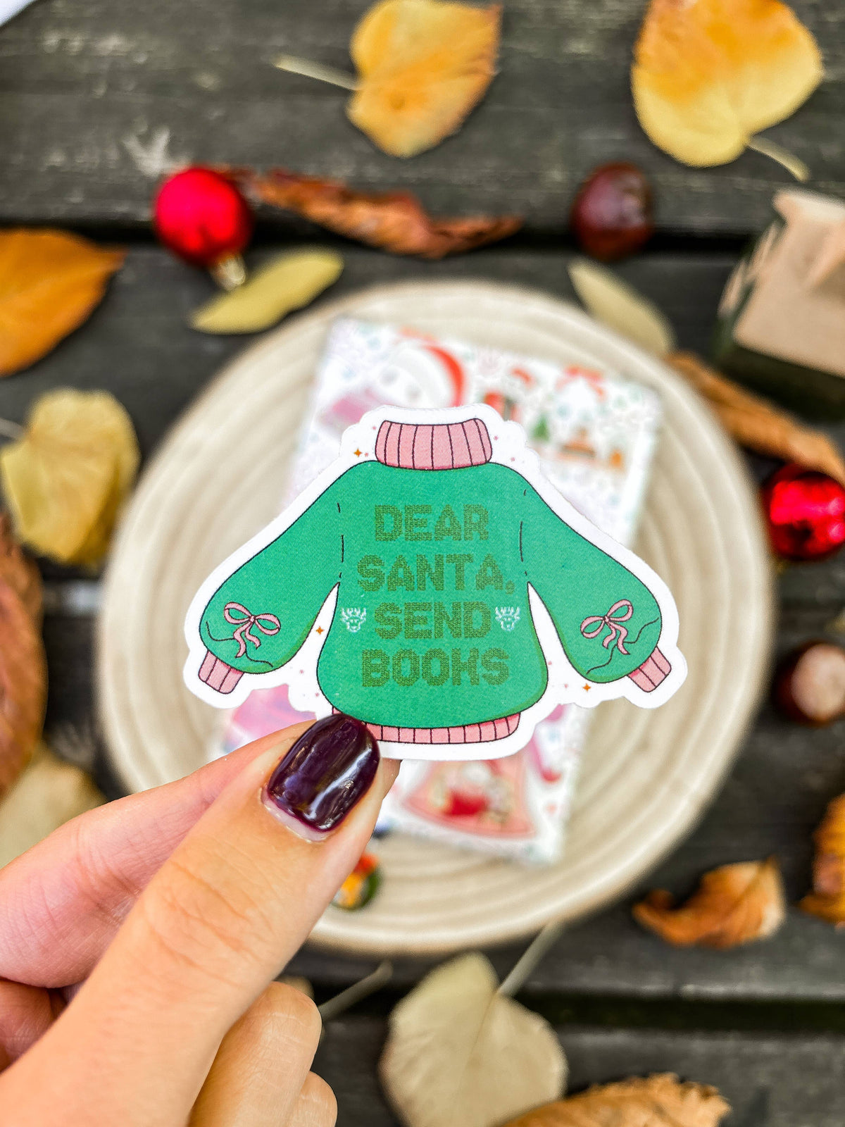 Vinyl sticker showing green “Dear Santa Send Books” sweater with bow cuffs