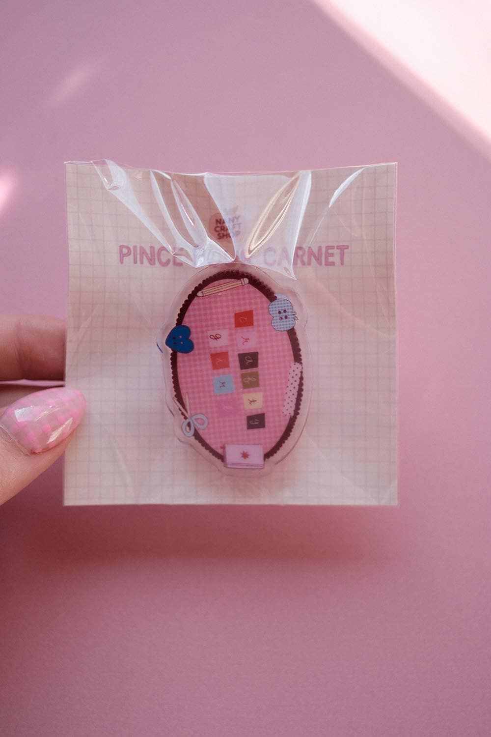 Oval fabric notebook clip on a backing card, with colorful squares and heart details