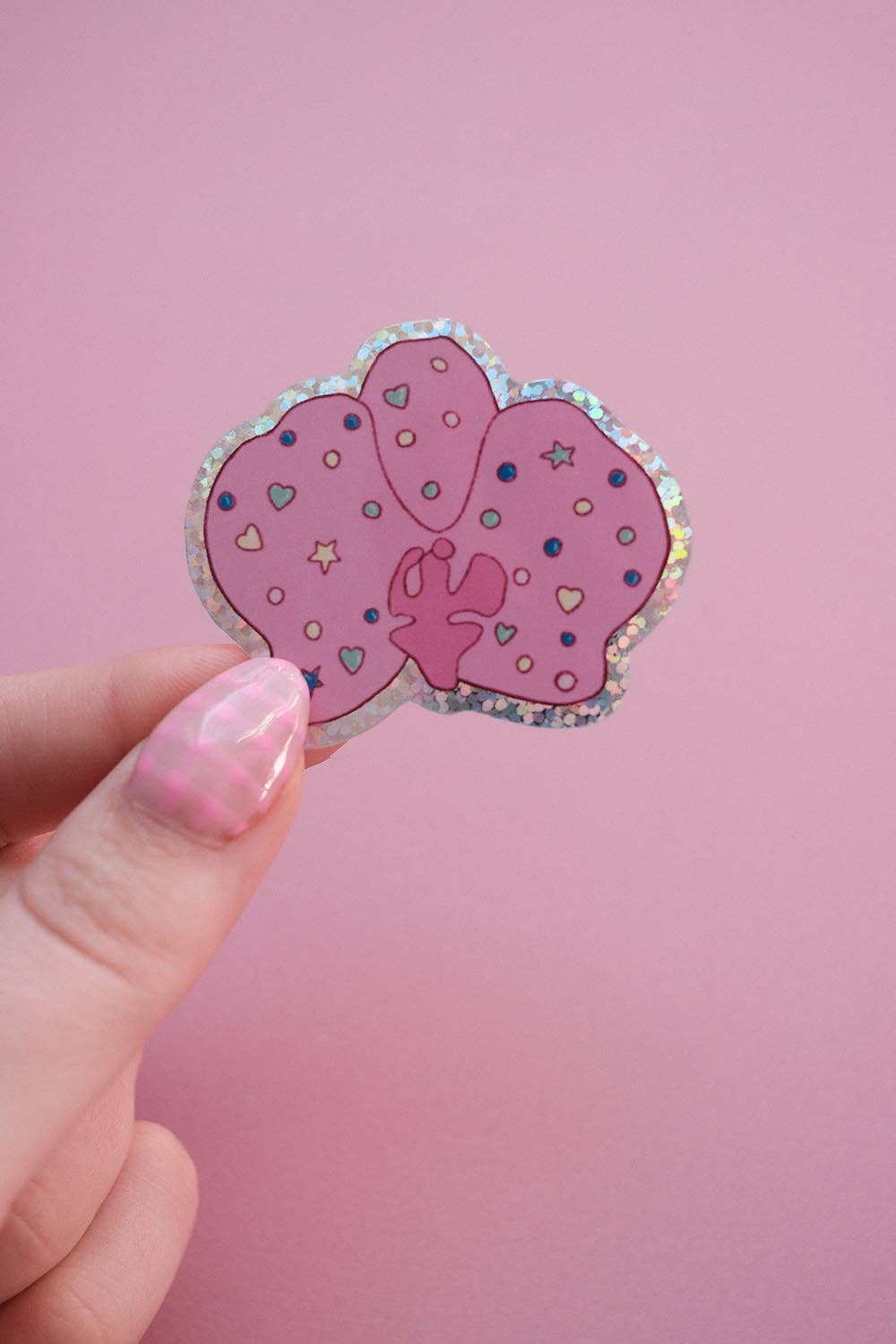 Hand holding orchid-shaped sticker with purple hearts and stars