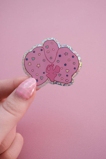 Hand holding orchid-shaped sticker with purple hearts and stars