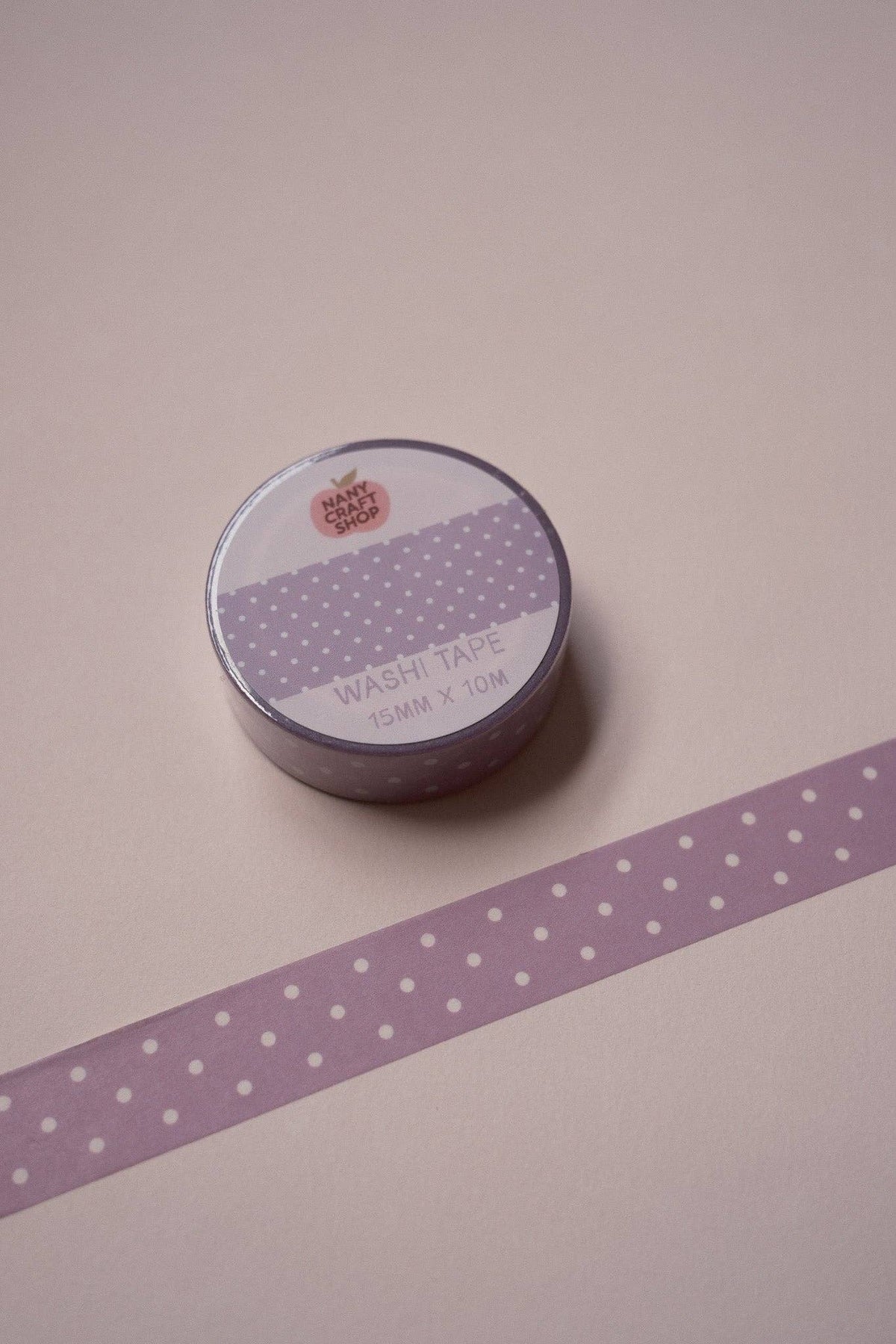 Purple polka dot washi tape roll with purple tape strip diagonally, white dot pattern
