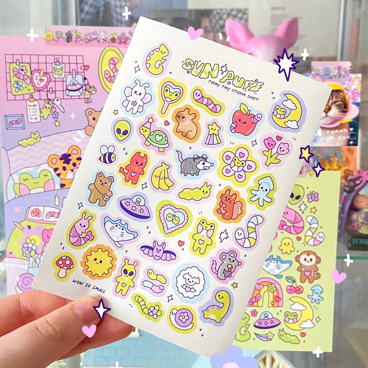Held mini sticker sheet with pastel cartoon animals, hearts, stars, and SUN PUFF title