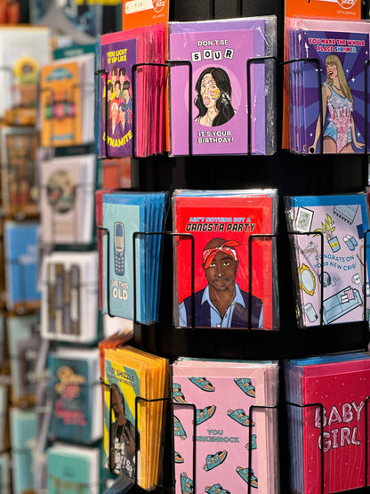 Birthday greeting cards with colorful illustrated covers, stacked in a display rack