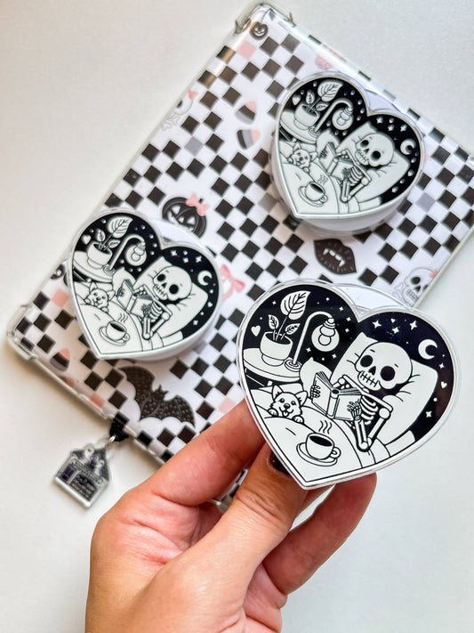 Clear checkerboard phone grip with cartoon heart magnets and small keychain charm.
