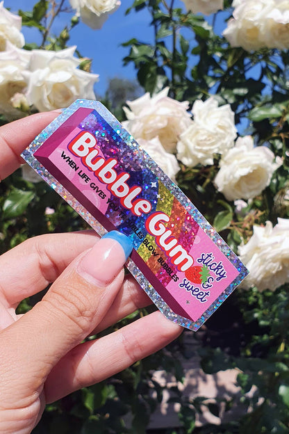 Glitter vinyl Bubble Gum sticker held between fingers outdoors