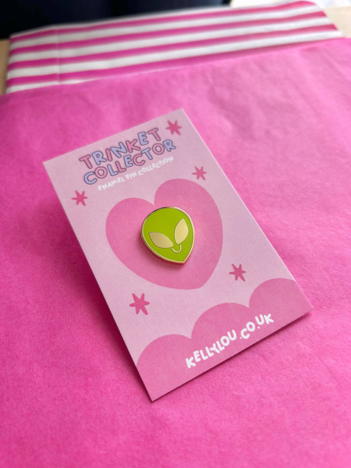 Alien head mini enamel pin on pink backing card, green face with yellow outline