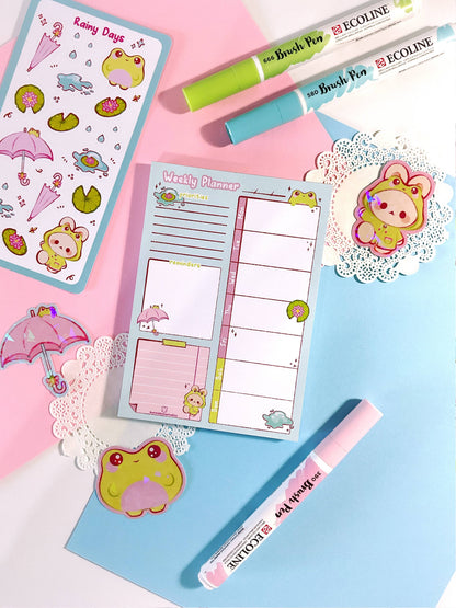 Rainy Days planner, pink cover with frog and umbrella icons, open weekly pages