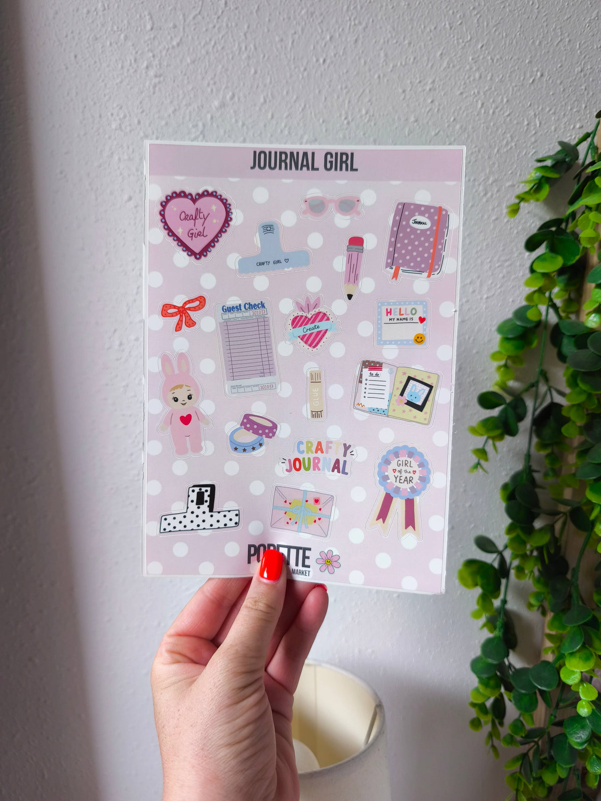 A5 sticker sheet held in hand, featuring journal cards, bunny figures, hearts and ribbons