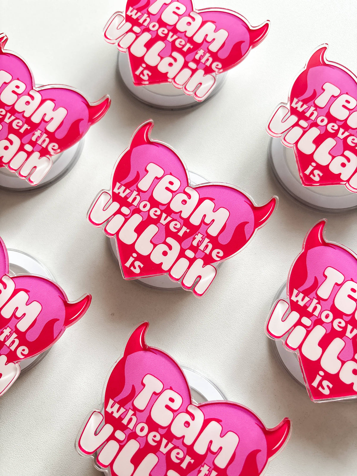 Pink devil heart magnetic grip with 'Team whoever the villain is' text