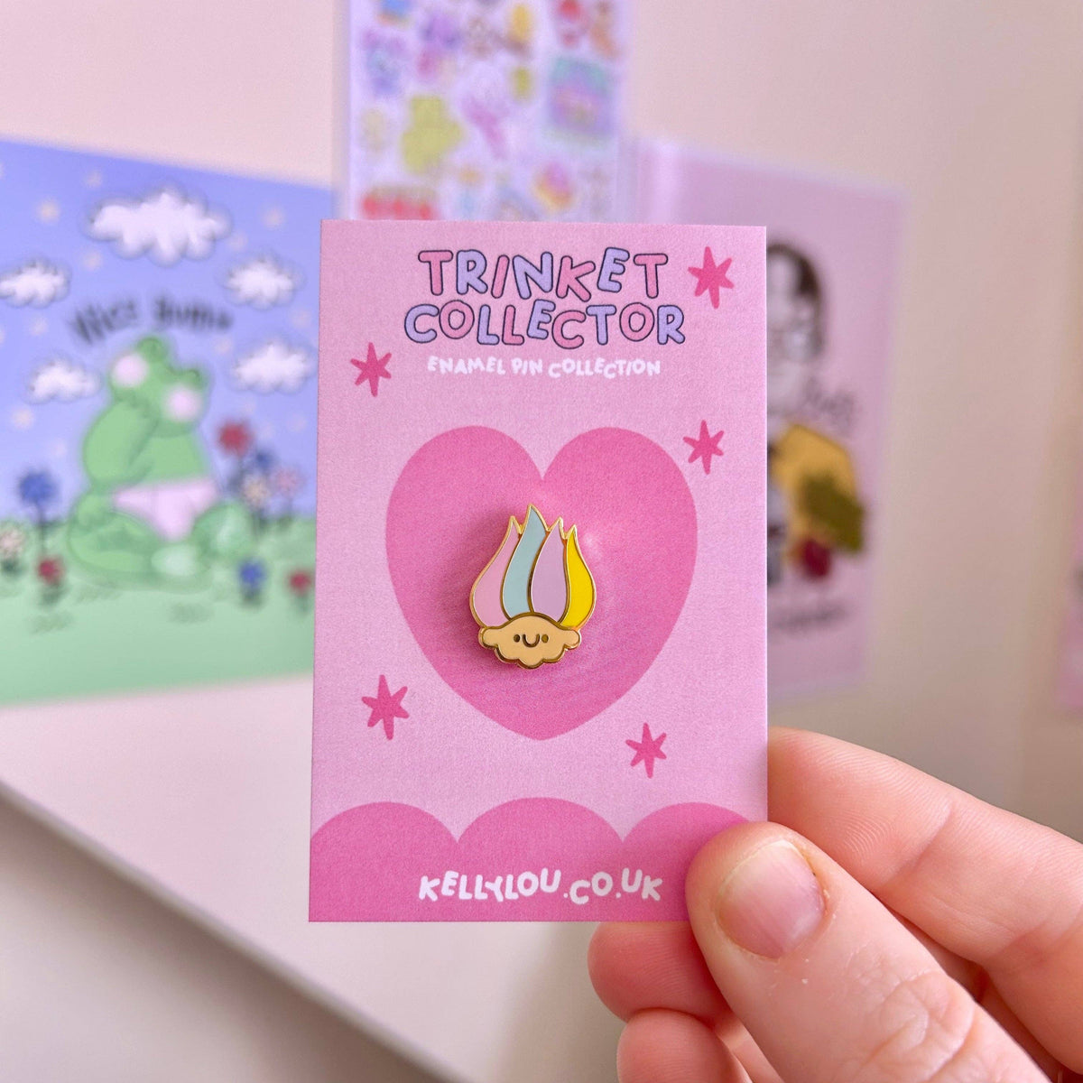 Mini troll head enamel pin, yellow hair and green cap, on pink card