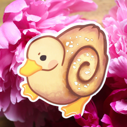 Vinyl sticker of a cartoon duck with a brown donut and white sprinkles
